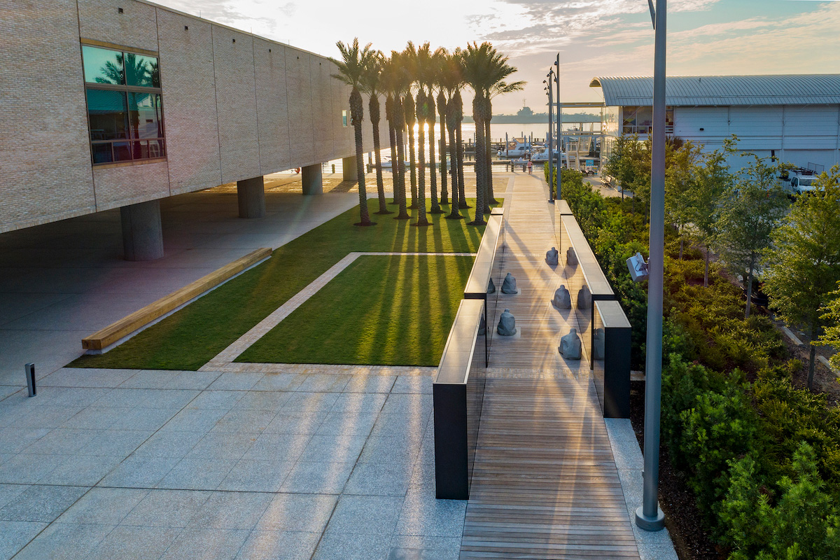 Exterior photo of the International African American Museum with a sunset cast against palm trees